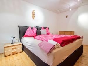 ein Schlafzimmer mit einem großen Bett mit rosa Kissen in der Unterkunft Apartment Höpperger by Interhome in Flaurling
