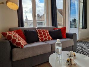 uma sala de estar com um sofá com almofadas e uma mesa em City Loft Apparthotel em Dijon