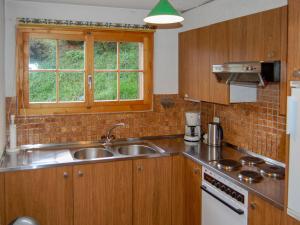 a kitchen with wooden cabinets and a sink and a window at Chalet Chalet Enfin by Interhome in Nendaz