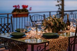 a table with plates and wine glasses on it at Villa Eris Amalfi Coast in Conca dei Marini