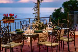 a table and chairs with glasses and plates on it at Villa Eris Amalfi Coast in Conca dei Marini