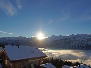 a view of the sun rising above the clouds in the mountains at Apartment Mountain Lake Panorama by Interhome in Sundlauenen