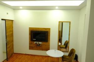 a room with a table and a tv on a wall at Hotel Girija Sunrise in Deoghar