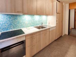 a kitchen with wooden cabinets and a sink at Apartment Allod Park Haus C 505 by Interhome in Davos +33 photos