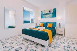 a white bedroom with a blue and orange bed at Villa Eris Amalfi Coast in Conca dei Marini