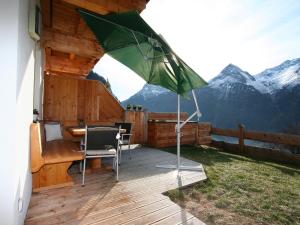 eine Terrasse mit einem Tisch und einem grünen Sonnenschirm in der Unterkunft Apartment s' HimmelReich-1 by Interhome in Huben