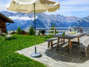 a picnic table with an umbrella and a grill at Chalet Chalet Jadi by Interhome in Nendaz