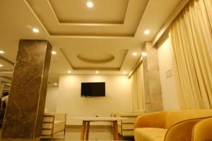 a living room with a couch and a tv on the ceiling at Hotel Girija Sunrise in Deoghar