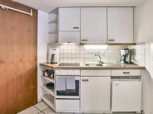 グリンデルワルトにあるApartment Chalet Abendrot-10 by Interhomeの白いキャビネットとシンク付きのキッチン