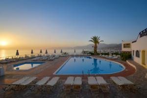 une grande piscine avec des chaises longues et l'océan dans l'établissement Hersonissos Village Hotel & Bungalows, à Chersónissos