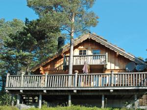 a log cabin with a porch and a tree at Holiday Home Knutebu - SOW093 by Interhome in Øyuvstad