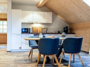 a kitchen with a wooden table and blue chairs at Apartment Schmalzenhof by Interhome in Hofstetten