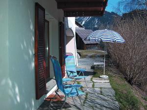 zwei Stühle und ein Regenschirm neben einem Gebäude in der Unterkunft Apartment Deli by Interhome in Alvaneu