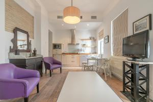 un soggiorno con sedie viola e TV di Hércules XCI Apartments a Siviglia