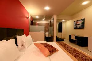 a bedroom with a white bed with a red wall at Tills at Vienna Hotel in Tema