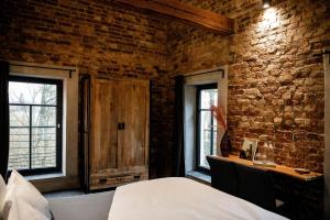 um quarto com uma parede de tijolos, uma cama e janelas em Wassermühle Deppendorf em Bielefeld