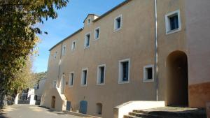 a large brown building with a tree next to it at GITE DES FRANCISCAINS-Imiza in Canari