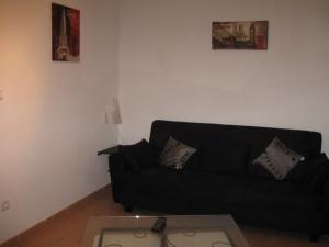 a living room with a black couch and a table at GITE DES FRANCISCAINS-Imiza in Canari