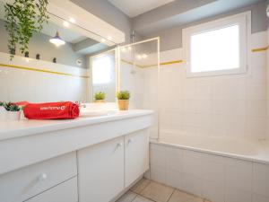 a bathroom with a sink and a tub and a window at Apartment Les jardins de l'Amitié by Interhome in Anglet