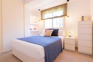 a white bedroom with a bed with a blue blanket at SW Mendoza 20 in Málaga