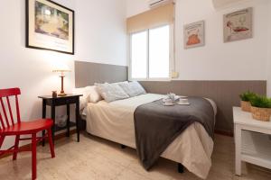 a small bedroom with a bed and a red chair at SW Soho Family Apartment in Málaga