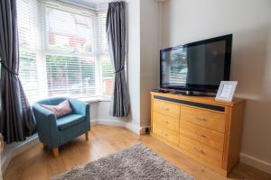 a living room with a television on a dresser with a chair at Stylish Home in the heart of the English Riviera in Torquay