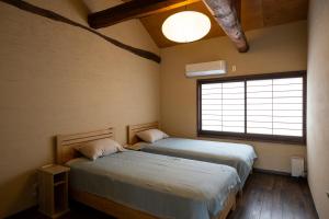 1 dormitorio con 2 camas y ventana en Hostel&Cafe Farolito en Ukiha