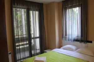 ein Schlafzimmer mit einem Bett und zwei großen Fenstern in der Unterkunft Winter Аpartments Gerovi in Pamporowo
