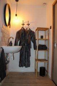 a robe hanging on a wall next to a sink at Grytmanshoeve, Vakantiehuis met glamping in Niawier