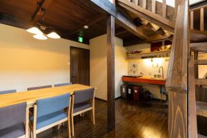 ein Esszimmer mit einem Holztisch und blauen Stühlen in der Unterkunft Hostel&Cafe Farolito in Ukiha