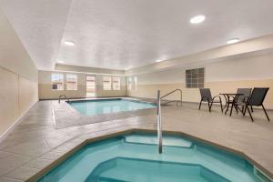 a swimming pool in a building with a table and chairs at Microtel Inn & Suites Lincoln in Lincoln