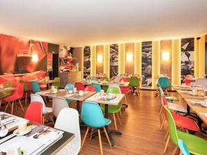 ザールブリュッケンにあるibis Saarbrücken Cityのテーブルとカラフルな椅子が備わるレストランを併設しています。