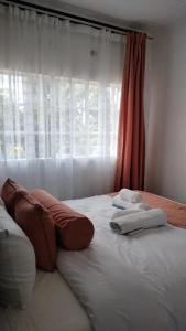 a large bed with two pillows and a window at Bloom private home in Thika