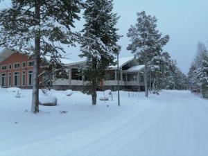 a building covered in snow with trees in the foreground at Baza Otdyha Lesnaya in Apatity