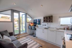 uma cozinha e sala de estar com um sofá e uma mesa em Papillon Southwold - A Modern Flat with Balcony em Southwold