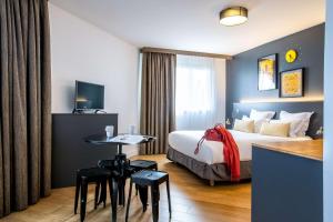 pokój hotelowy z łóżkiem i stołem z krzesłami w obiekcie Best Western Plus Suitcase Paris La Défense w mieście Bois-Colombes