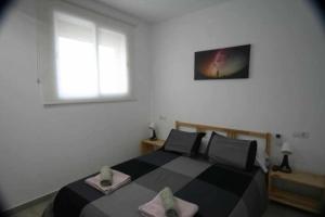 Un dormitorio con una cama en blanco y negro y una ventana en Minva apartamento junto al mar, en Grao de Castellón