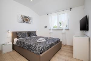 a white bedroom with a bed and a tv at Villa Irena in Medulin