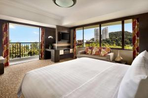a hotel room with a bed and a tv and windows at Shangri-La Golden Sands, Penang in Batu Ferringhi