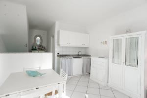 uma cozinha branca com armários brancos e uma mesa em Monolocale Il Porto 3 em Porto Azzurro