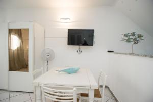 uma sala de jantar branca com uma mesa e cadeiras brancas em Monolocale Il Porto 3 em Porto Azzurro
