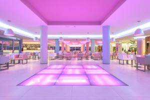 a restaurant with purple lighting and tables and chairs at Hotel Garbi Ibiza & Spa in Playa d'en Bossa +186 photos