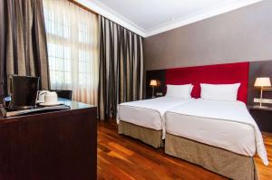 a bedroom with a large bed and a red headboard at Hotel NH Poznan in Poznań