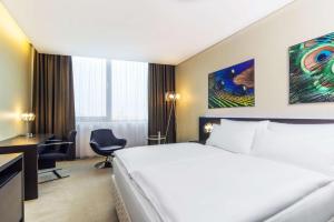 a hotel room with a large bed and a desk at NH Bratislava Gate One in Bratislava