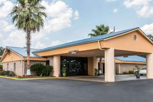 a hotel with a palm tree in front of a building at Quality Inn Hinesville - Fort Stewart Area, Kitchenette Rooms - Pool - Guest Laundry in Hinesville