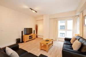 a living room with a couch and a tv at Skyline Plaza By Viridian Apartments in Basingstoke