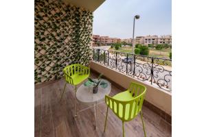 einen Balkon mit 2 grünen Stühlen und einem Tisch in der Unterkunft The Bold Parisian House - Steps From The Best Mall in Cairo in Kairo