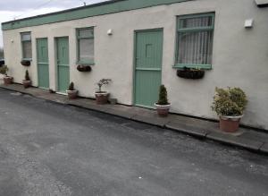 a row of green doors on a building with potted plants at The Old Colliery Stables in Durham