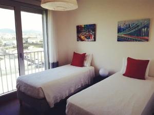 two beds in a hotel room with a window at Home at Azores - City View Apartment in Ponta Delgada