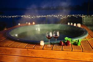 a hot tub with two glasses of wine and roses at Z widokiem na jezioro in Iława
